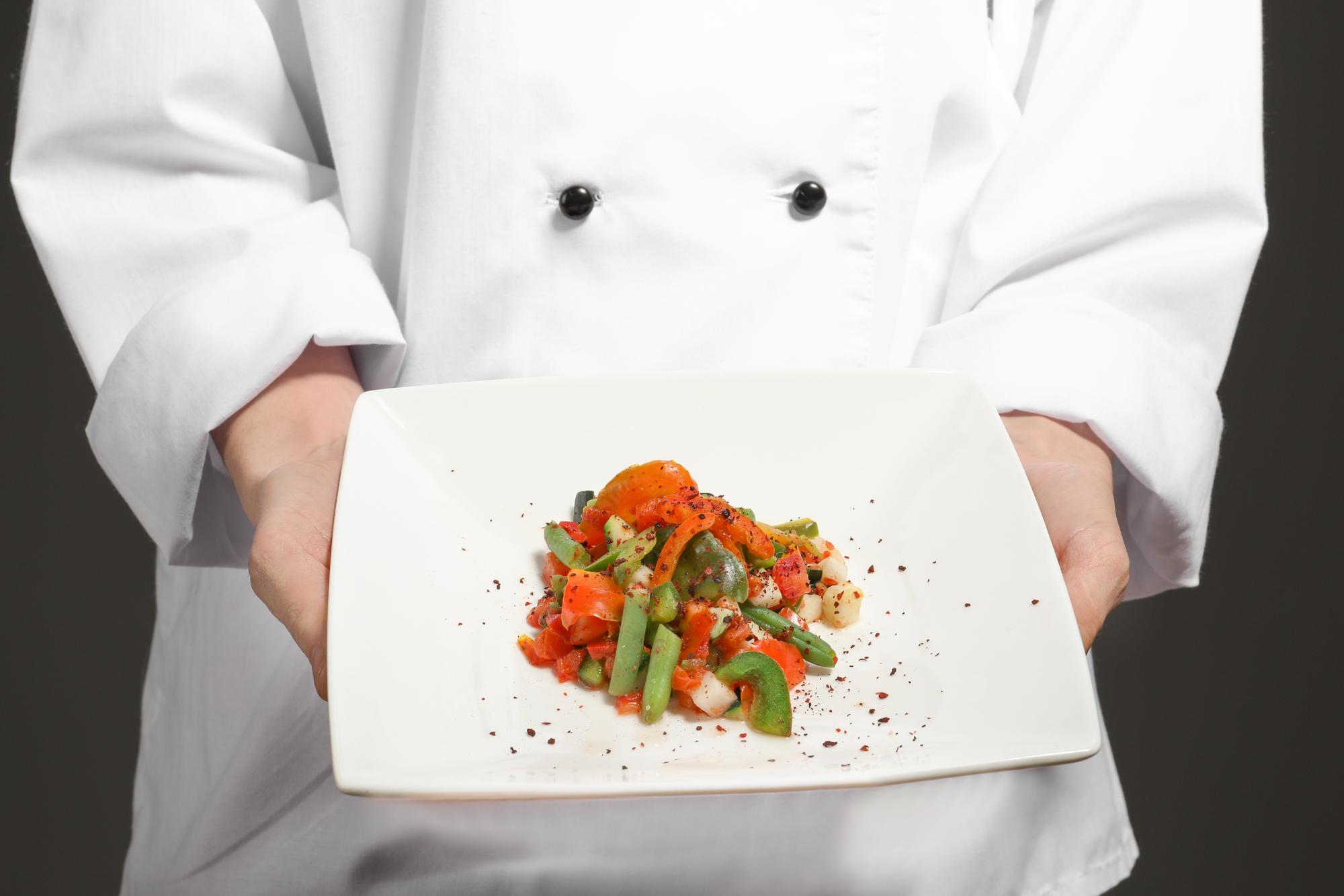 Chef presenting plated dish in a studio
